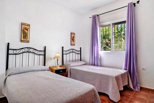 two beds in a room with purple curtains and a window at Villa Perez Zara Paco in Campano