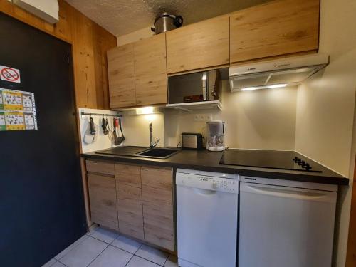 - une cuisine avec des placards en bois et un lave-vaisselle blanc dans l'établissement Studio Confort pour 3 avec Balcon Sud, Pied des Pistes, Animaux Acceptés - FR-1-452-289, aux Menuires