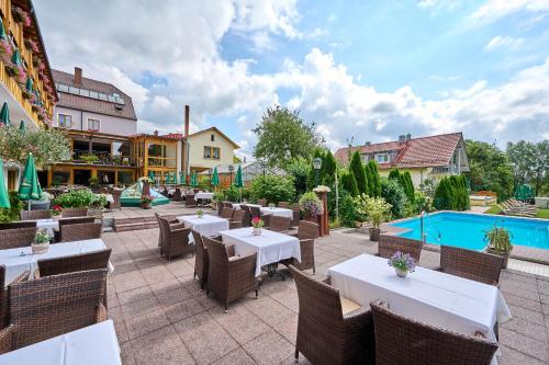 a patio with tables and chairs and a swimming pool at Hotel Restaurant Zum Goldenen Anker mit Hallenbad in Windorf