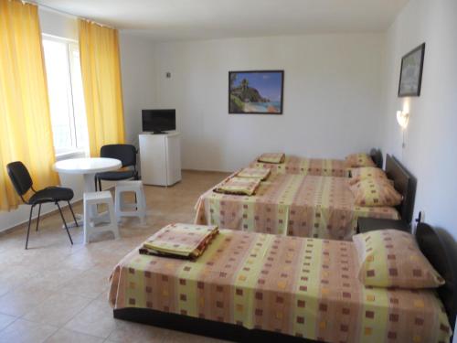 a hotel room with two beds and a table and chairs at Стаи под наем "Таня"- безплатен паркинг на 100 метра in Ahtopol