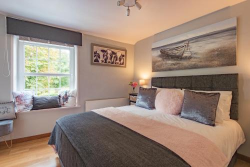 a bedroom with a large bed and two windows at Cow and Cockle - quirky cottage in the centre of Deal in Deal