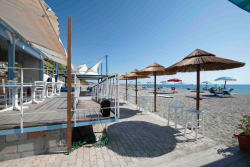 una spiaggia con alcune sedie e ombrelloni e l'oceano di Grand Hotel La Tonnara ad Amantea
