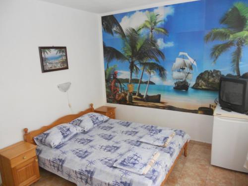 a bedroom with a bed and a painting on the wall at Вила "Таня" in Ahtopol