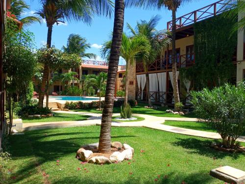 a palm tree in the grass next to a building at Serrote Apartamento in Jericoacoara