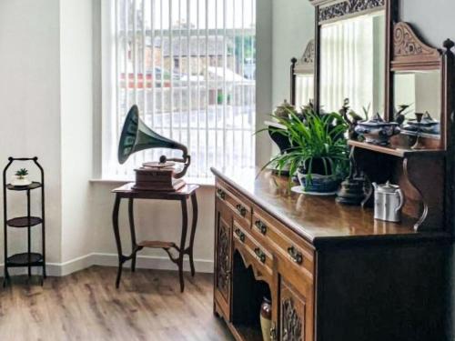 a room with a wooden dresser with a mirror and plants at The Legion in Saint Margarets Hope