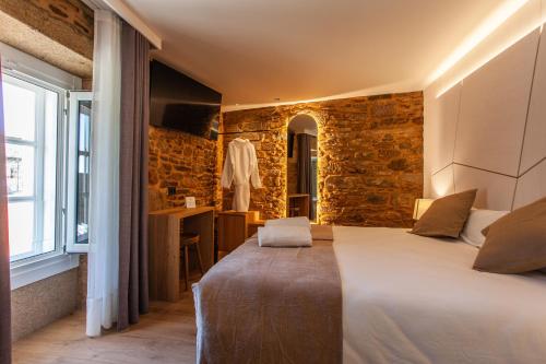 a bedroom with a large bed and a stone wall at Hotel Plaza Obradoiro by Bossh! Hotels in Santiago de Compostela