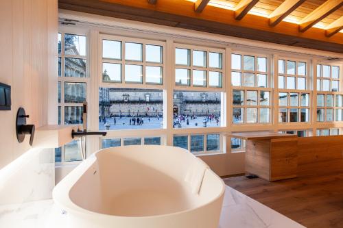 eine große Badewanne in einem Zimmer mit einem großen Fenster in der Unterkunft Hotel Plaza Obradoiro by Bossh! Hotels in Santiago de Compostela