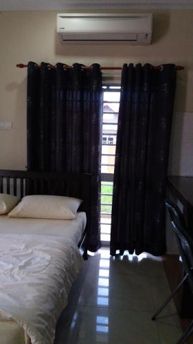 a bedroom with two beds and a window with black curtains at GLG KLIA Transit House in Sepang