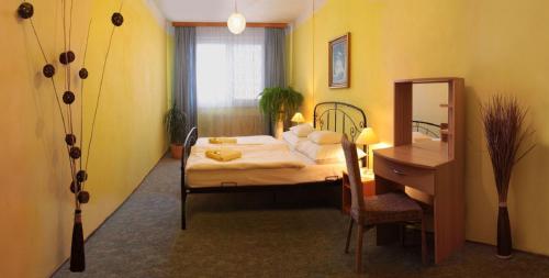 a bedroom with a bed and a desk and a mirror at Hotel Cementář in Hranice