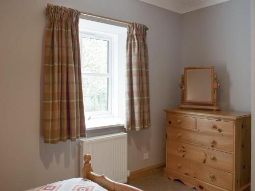 1 dormitorio con ventana, tocador y espejo en The Barn, en Fintry