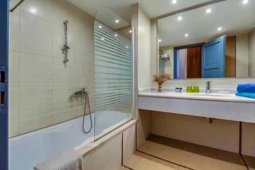a bathroom with a shower and a tub and a sink at Istron Collection Villas in Istron