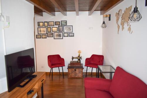 a living room with two red chairs and a tv at Casa das Gémeas - Moradia rústica in Castelo de Vide