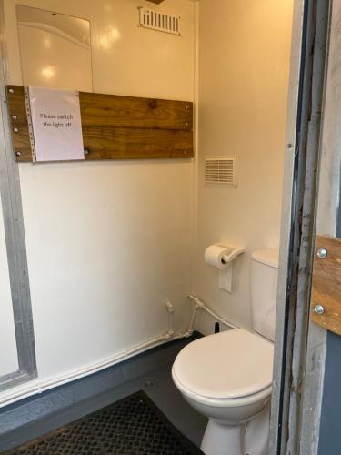 a bathroom with a toilet and a sign on the wall at The Shepherd's Hut - Wild Escapes Wrenbury off grid glamping - ages 12 and over in Baddiley