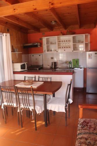 una cocina con mesa de madera y sillas. en cabaña en Pichilemu, en Pichilemu