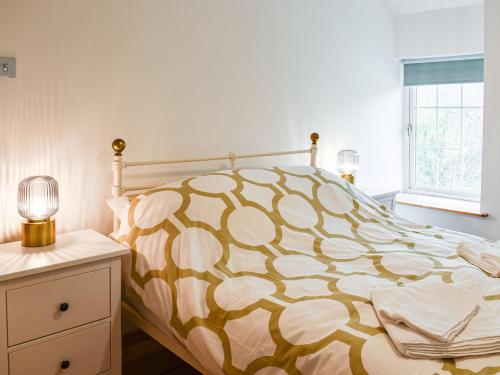 a bedroom with a bed with a yellow and white comforter at 2 White Horses Cottages in Pwllheli