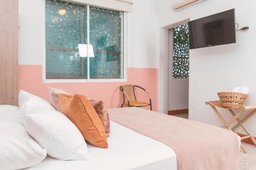 a bedroom with a white bed with pink walls and a window at Casa de Pinos Hotel Boutique in Bucaramanga