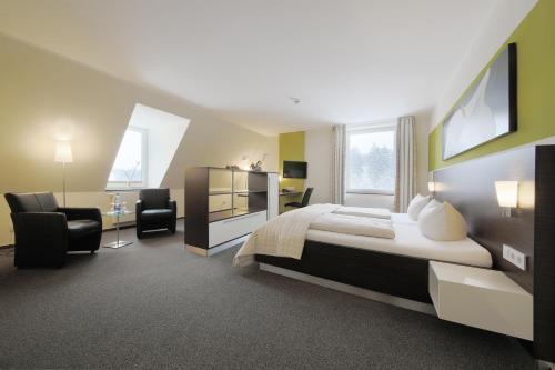 a bedroom with a bed and a desk and chairs at Sporthotel Fuchsbachtal in Barsinghausen