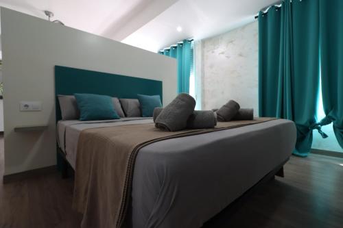 a bedroom with a large bed with blue curtains at Carthago Suites in Cartagena
