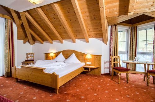 een slaapkamer met een groot bed en een tafel en stoelen bij Hotel Garni Daniel in Ischgl