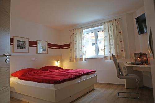 ゴーザウにあるZeilner Dachstein Apartmentのベッドルーム1室(赤いベッド1台、窓付)