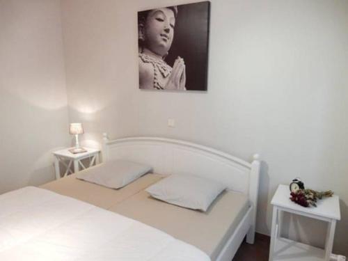 ein Schlafzimmer mit einem weißen Bett mit einem Bild an der Wand in der Unterkunft Villa Marie Oli in Nieuwpoort