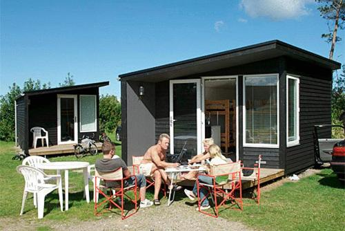 フレデリクスハウンにあるFrederikshavn Nordstrand Camping & Cottagesの小さな家の外のテーブルに座る人々