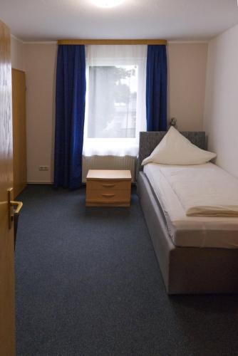 a bedroom with two beds and a window with blue curtains at Haus Magdalene in Bad Schwartau