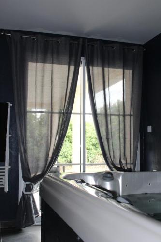 a kitchen with a window with curtains and a sink at Althéa, gîte de charme et bien être in Fontenay-le-Comte