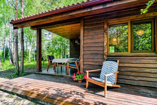 a wooden cabin with a table and chairs on a deck at Beržų namelis - Birch cabin in Kučiūnai