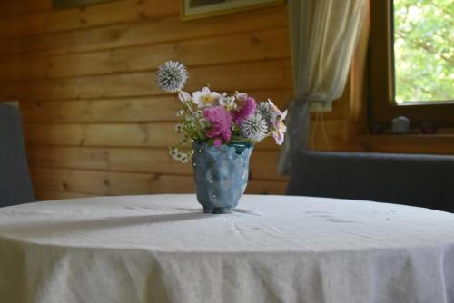 a blue vase filled with flowers sitting on a table at Beržų namelis - Birch cabin in Kučiūnai