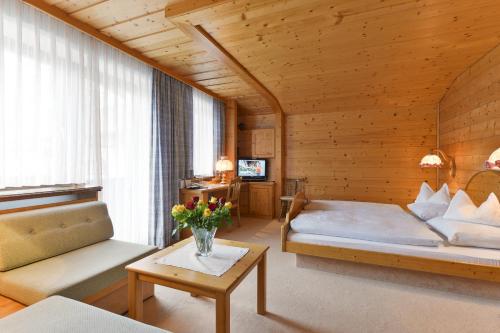 レッヒにあるHotel Bergheimのベッドルーム1室(ベッド2台、ソファ、テーブル付)