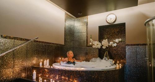納爾瓦約埃蘇的住宿－納爾瓦約埃蘇醫療Spa酒店，妇女在带时钟的浴室的浴缸里