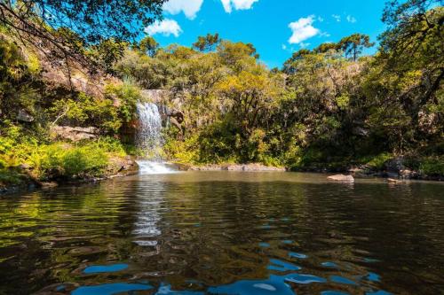 a waterfall in front of a body of water at Chalés Rota das Cachoeiras in Urupema