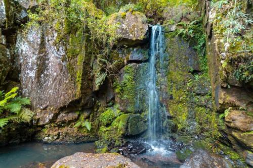 a waterfall on the side of a rock wall at Chalés Rota das Cachoeiras in Urupema