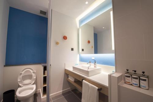 a bathroom with a toilet and a sink and a mirror at Holiday Inn Express Tianjin Binhai by IHG in Binhai