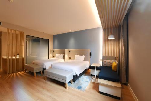 a hotel room with two beds and a bench at Holiday Inn Express Tianjin Binhai by IHG in Binhai