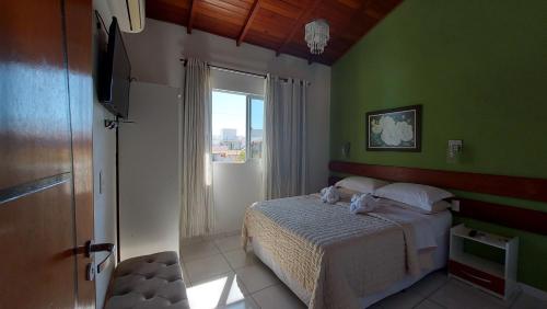 um quarto com uma cama com paredes verdes e uma janela em Pousada Estrela Guia em Florianópolis