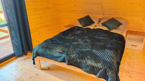 a bedroom with a bed with a black comforter at Domek nad Nieliszem in Nielisz