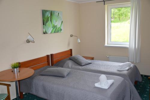 dwa łóżka w pokoju ze stołem i oknem w obiekcie Hotel Chojnik w mieście Podgórzyn
