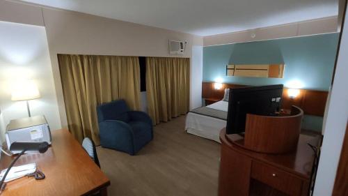 a hotel room with a bed and a blue chair at Flat Borges Lagoa Ibirapuera c/ garagem UH407 in Sao Paulo