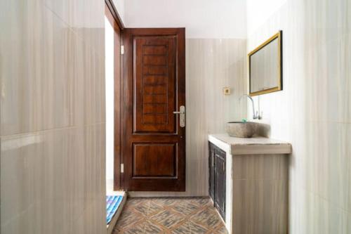 a bathroom with a sink and a wooden door at Padanta Gili Trawangan in Gili Trawangan