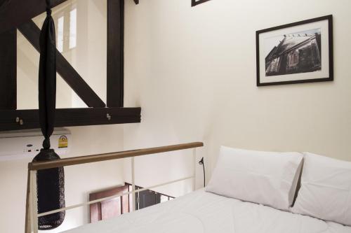 a bedroom with a white bed with white pillows at Baan Luang Rajamaitri Historic Inn in Chanthaburi
