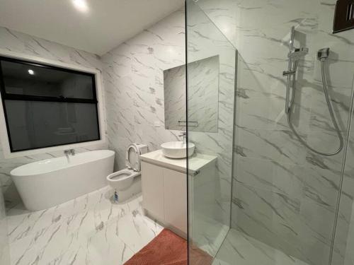 W łazience znajduje się prysznic, toaleta i umywalka. w obiekcie ‘The bayside’ Beautifully brand new house w mieście Mentone