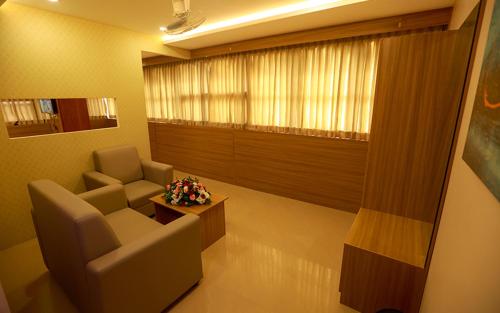 a waiting room with a couch and a chair and a table at Hotel Emirates in Kānnangād