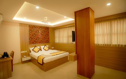 a hotel room with a bed and a television at Hotel Emirates in Kānnangād