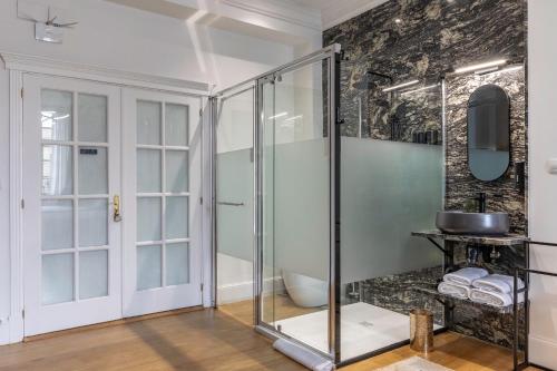 y baño con ducha de cristal y pared. en Habitaciones Apartamento B&B Plaza Nueva 8, en Bilbao