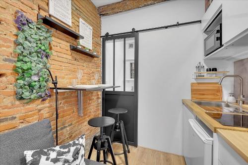 une cuisine avec un mur en briques et deux tabourets de bar dans l'établissement Getaway For 2 Beautiful Studio Near The Garonne, à Toulouse