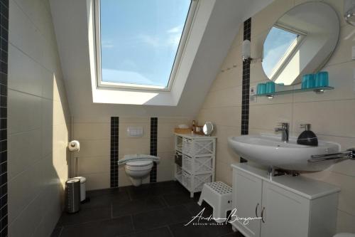 ein Bad mit einem Waschbecken und einem WC mit einem Dachfenster in der Unterkunft Pension Lütje Huske Zimmer 3 in Südbrookmerland