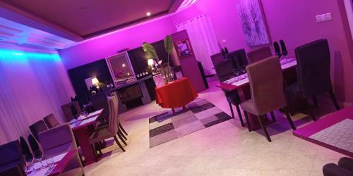 a room with purple lights and tables and chairs at L'Address in Cotonou