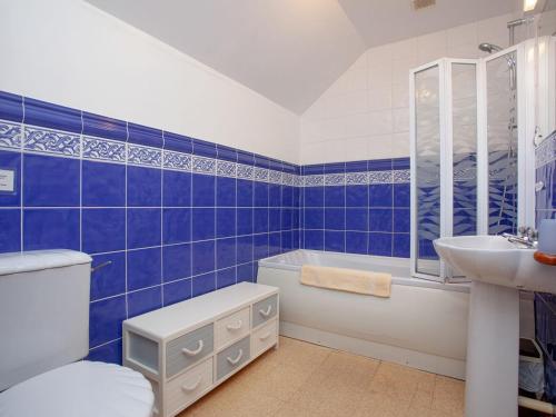 a blue tiled bathroom with a toilet and a sink at The Coach House - Uk35953 in South Pool